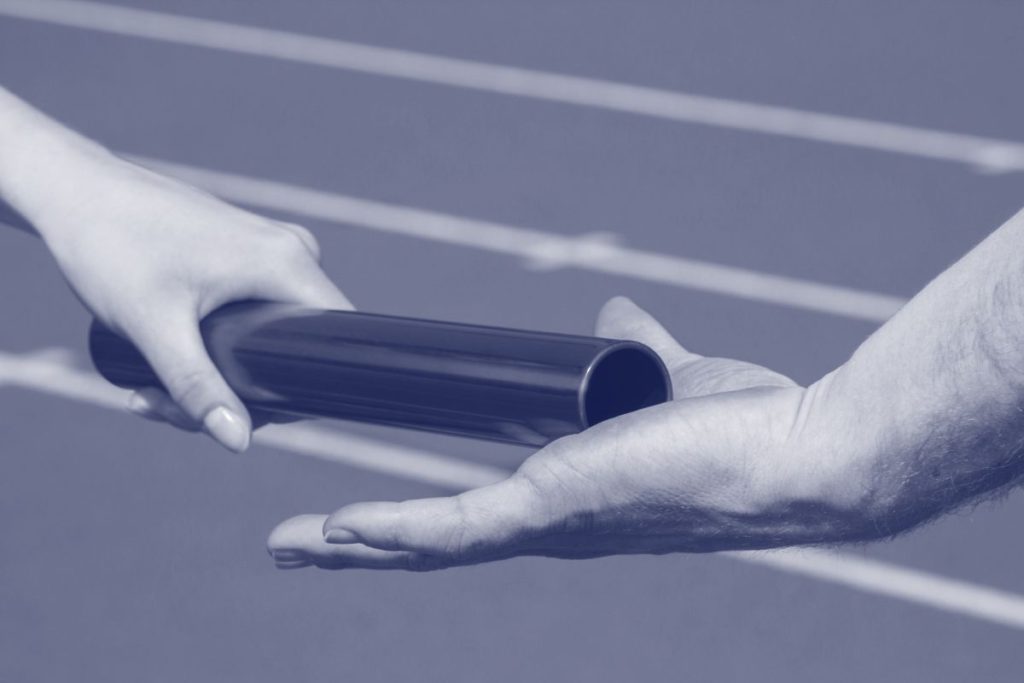 Two hands passing a baton in a relay race.