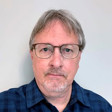 Headshot of Howard with glasses and a blue plaid shirt.